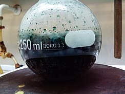 Mezcla crómica, ya reducida, en plena ebullición. El color verde se debe a los iones Cr(III) que se obtienen como producto.