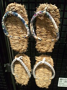 The caption, and the museum sign in the image, call these Wiktionary:わらじ "waraji". But other sources[1] insist that thong-style straw sandals are ぞうり, zōri, and that if the straps are covered in cotton, as these appear to be, they are fuku-zōri.