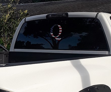 星条旗のテクスチャで塗り潰された「Q」のデカールが貼られている車の窓