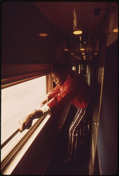 File:SLEEPING CAR ATTENDANT TAKES A LOOK AT THE PASSING SCENE BETWEEN DUTIES ON THE EMPIRE BUILDER ENROUTE FROM CHICAGO TO... - NARA - 556079.jpg