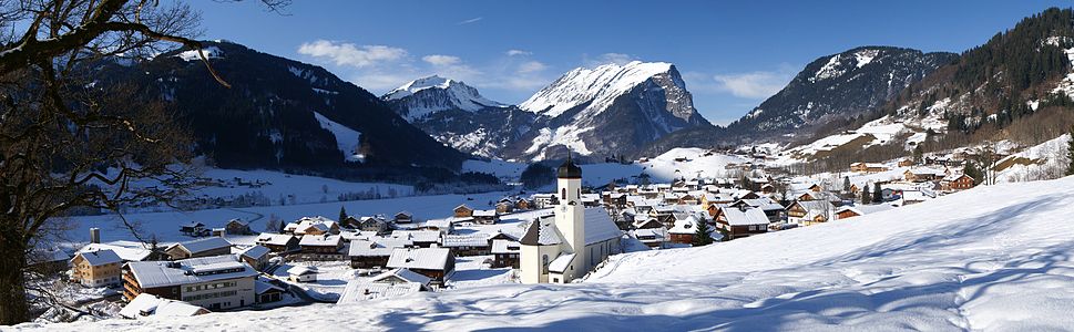 Aralık ayında Schoppernau'nun paoramik görünümü (Karşıda kendine has şekli ile Kanisfluh dağı, önde Göfis belediyesine bağlı yerleşim ve bölge kilisesi)]. (Böhringer)