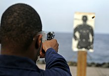 A sailor shooting at a "Colt Police Silhouette Target" US Navy 090424-N-7280V-262 Operations Specialist 3rd Class Chazz Brown fires a 9mm pistol during a small arms qualification aboard the amphibious command ship USS Blue Ridge (LCC 19).jpg