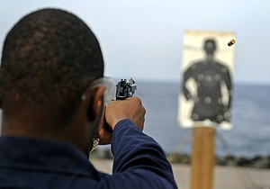Um marinheiro treinando tiros em um "Colt Police Silhouette Target", proposto e defendido por "Fitz"