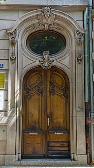 Wooden door with a round window above it, in Strasbourg
