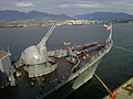 Vista próxima dos canhões de calibre duplo AK-130 na proa, e costa norte de Vancouver ao fundo.