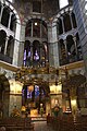 Notranjost visoke osmerokotne cerkve, ki se dviga v treh vrstah okrašenih lokov. Nad osrednjim oltarjem visi velik svečnik.