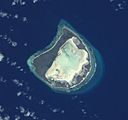 Astove Atoll, slightly oblique view from space.Note the wide land area (dark) surrounding the whitish lagoon