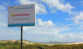 Placa fixada na praia em São Luís, contendo a frase: A água neste ponto encontra-se imprópria.