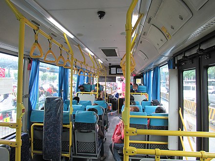 Interior of a low-floor city bus in Manila, showing 2-3 seating, space for wheelchairs and grab rings for standing passengers