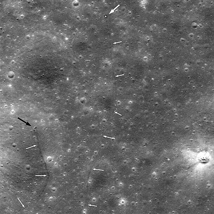 Lunar Reconnaissance Orbiter image of Lunokhod 2 and its tracks. The large white arrow indicates the rover, the smaller white arrows indicate the rover's tracks, and the black arrow indicates the crater where it picked up its fatal load of lunar dust.[14]