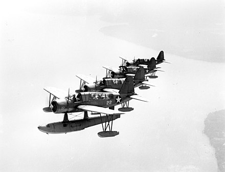Four OS2U Kingfisher airplanes flying in right echelon formation.