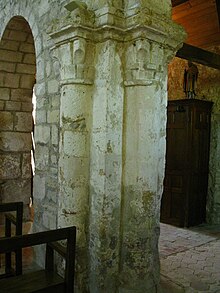 Pilares unidos a un arco;  se ven dos capiteles decorados con motivos vegetales.