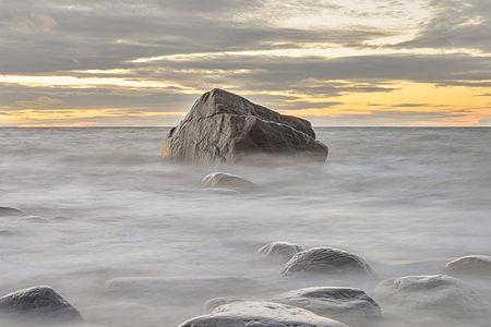 Cape Purakkari, the northernmost point in mainland Estonia, at the end of October. Weather was very windy (up to 20 m/s), water level was high and sun had just set down moments ago. There are glacial boulders in the picture. Long exposure makes the waves look like mist.