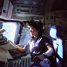 l'astronaute Sally K. Ride au contrôle des boîtes de commandes, dans le siège du pilote.