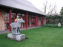 ☎∈ Wolfson College, Cambridge, showing the Chinese-style Lee Hall, a stone with Chinese-character inscriptions on the right, and a statue with a student next to it.