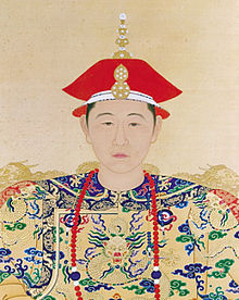 Chân dung màu toàn mặt, đầu và vai của một người trẻ tuổi mặc đeo dây chuyền màu đỏ, khoác hoàng bào màu vàng có hình rồng và hoa văn màu xanh dương, xanh lá và đỏ.