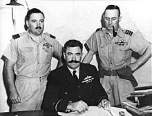 Half-length portrait of three military men behind a desk, all with pilot's wings on left breast pocket