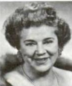 A smiling middle-aged white woman with light wavy hair in a bouffant updo