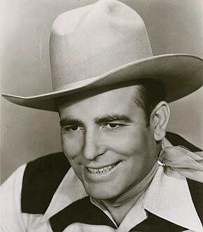 A man smiling broadly while wearing a cowboy hat
