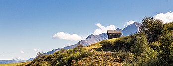 Vista (a partir de Surcuolm) de um galpão em Cuolm Sura, cantão dos Grisões, Suíça. Ao fundo aparecem nuvens sobre as montanhas no lado sul do vale. A população de Surcuolm fala tradicionalmente o romanche. Ao contrário dos assentamentos vizinhos de Flond e Luven, no entanto, é católico. Em meados do século XIX, as famílias yeniches foram naturalizadas com base na lei de combate à falta de moradia. Surcuolm experimentou um grande desenvolvimento nos últimos anos, principalmente devido à conexão com a área de esqui de Obersaxen. (definição 5 147 × 1 967)