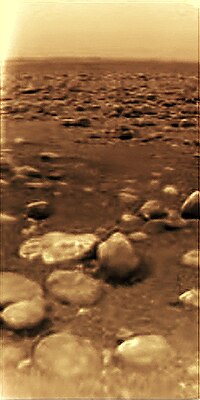 Imatge in situ de la superfície de Tità per la Huygens—l'única foto de la superfície d'un cos planetari fora del Sistema Solar interior. (Les imatges d'esquerra i dreta són l'abans i el després del processament d'imatge, respectivament.)