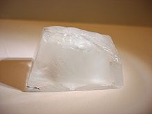 An ice cube resting on a white surface