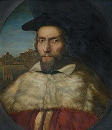 Een portret van een blanke man met een baard van middelbare leeftijd in academische gewaden en pet.