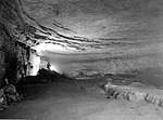 A cave with layered rocks. At the end of the cave there is a light.