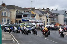Několik motocyklových závodníků na cestě do levého rohu.