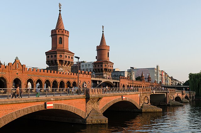 גשר אוברבאום הוא גשר דו-מפלסי החוצה את נהר השפרה בברלין. הגשר משתרע מהחלק השמאלי התחתון של התמונה, לחלק הימני העליון. במרכז התמונה ניתן לראות את שתי המגדלים הגותיים שבמרכז הגשר, להם צריחים אדומים. הגשר אדום, במרכז התמונה שתי קשתות, ועליהן המפלס התחתון הכולל כביש שעליו להולכי רגל, משמאלו, מעל שורת קשתות, והמפלס העליון המיועד לקווי האו באן.