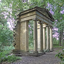 An arch with columns and a pediment standing alone in a woodland