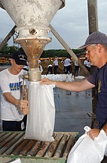 Manual filling of sandbags from a hopper or silo
