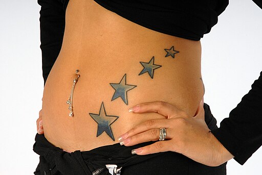 Woman with four star tattoos on her belly, and a navel piercing