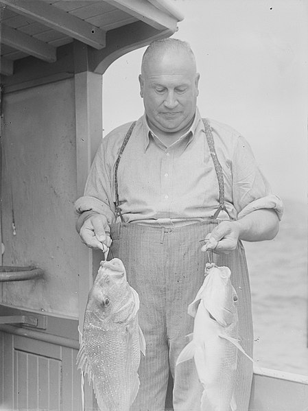 File:A man holding two fish (AM 88339-1).jpg