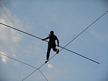 Photographie d'un homme marchant sur un fil.