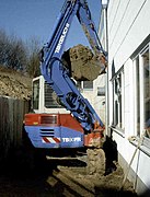 Tranchée creusée au ras d'un mur en déportant la flèche d'une minipelle.