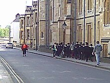 Choristers from New College School in gowns and mortarboards 'crocodile' to rehearsal in New College New College School Oxford pupils in regalia.jpg