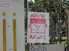 Skilt på porten til Government House med tegning af Thaksin og teksten "Get out" (forsvind), 4. april.