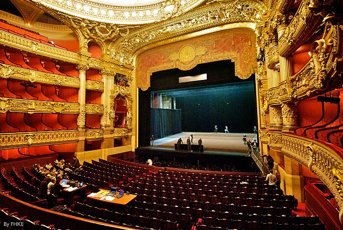 The interior of the Palais Garnier, an opera house, showing the stage and auditorium, the latter including the floor seats and the opera boxes above