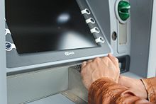 Une personne couvrant un clavier ATM avec sa main tout en tapant le code PIN