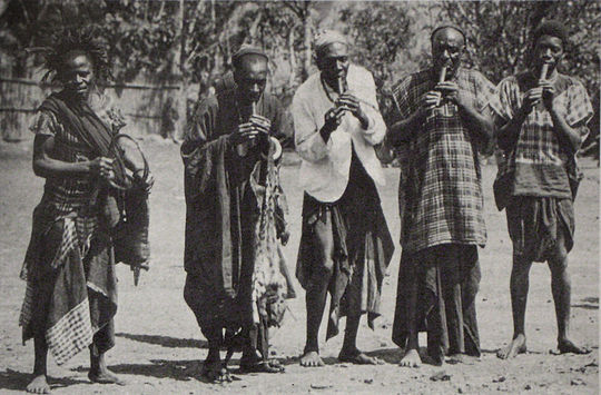 Lela celebrations in Bali, Cameroon, around 1908. Four men play on holy lela flutes. The celebrations are directed by members of the Bali royal family.