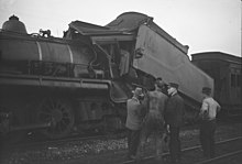 Railway workers looking at the damaged train tender after a crash at Tamaree, October 1947.jpg