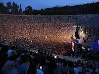 Sold-out stadium crowd, surrounding a stage