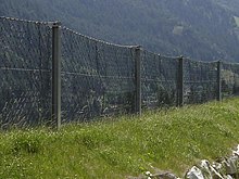 A net with a rectangular mesh, supported by static posts, placed on top a rockfall protection embankment. (Gothard pass, Switwerland) Static barrier.jpg