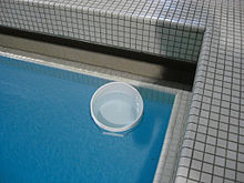 An indoor swimming pool appears cyan from above, as light reflecting from the bottom of the pool travels through enough water that its red component is absorbed. The same water in a smaller bucket looks only slightly cyan, and observing the water at close range makes it appear colorless to the naked eye. SwimmingPoolAndBucket.jpg