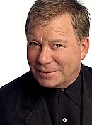 A man with short, brown hair, looking slightly upwards to the camera while smiling.