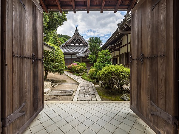 Wooden gate with open double door leading to the garden of Isshinin Buddhist temple in the compounds of Chion-in Kyoto Japan