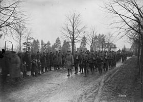 Photographie en noir et blanc de militaires marchant sur un chemin avec d'autres militaires se tenant sur le côté du chemin