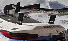 Example for an artificially created, totally misleading image: A race car exhibited at an airport (below) was cropped and combined on a computer with snowy mountains, leading to an image of a situation which never existed. BMW M8 GTE endurance race car in front of Tyrolian mountains - photomontage.jpg