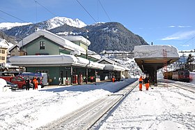 Sporene, hovedplattformen og passasjerbygningen til Airolo stasjon under et tykt lag med snø.